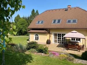 ein gelbes Haus mit einer Bank und einem Regenschirm in der Unterkunft Chalupa u Pavelků 