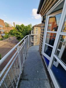einen Balkon mit weißem Geländer neben einem Gebäude in der Unterkunft Room in a shared Flat in London