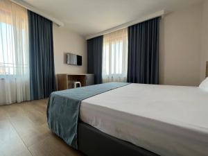 a bedroom with a large white bed in front of windows at Stamatovi Family Hotel in Pomorie