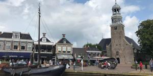 a building with a clock tower next to a river at Bungalow Plattedijk 25-34 in Lemmer