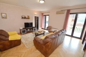 een woonkamer met 2 leren banken en een televisie bij Nikola - Two Bedroom Ap. with SeaView in Kotor