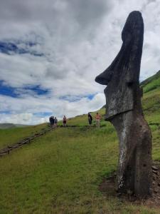 um grupo de pessoas andando em uma colina gramada em Moehiva Camping Rapa Nui em Hanga Roa