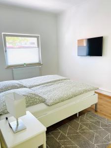 a white bedroom with a bed and a window at Bungalow-Wohnung nahe Flughafen Hamburg in Norderstedt