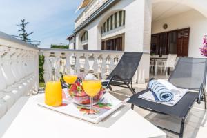 a table with two glasses of orange juice on a balcony at Tinel Apartment Sukosan in Sukošan