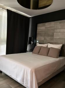 una camera da letto con un grande letto con lenzuola bianche e cuscini marroni di Superbe appartement avec balnéo. a Saint-Cyprien