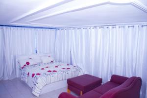 a white bedroom with a bed and a couch at Hôtel Amazone in Cotonou