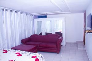 a living room with a red couch and a bed at Hôtel Amazone in Cotonou