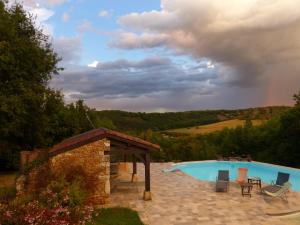 a pool with chairs and a gazebo and a rainbow in the sky at Chambres D'Hôtes Les Boudines in Saint-Germain-de-Belvès