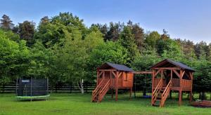 two wooden play structures in a field with trees at Roztoczańska Ostoja in AdamÃ³w