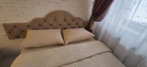 a bed with a headboard and two pillows and a window at Inessa Center Guest PenthHouse in Chişinău