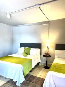 - une chambre avec 2 lits avec des draps blancs et verts dans l'établissement Hotel El Pedregal, à Matehuala