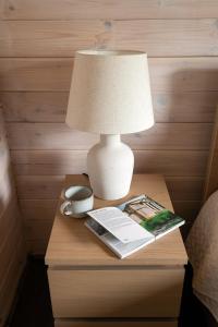 Forrest Guest House في Ķesterciems: مصباح على طاولة مع كتاب ومجلة