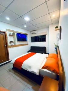 una camera da letto con un grande letto con lenzuola bianche e arancioni di Hotel Madrigal a Portoviejo