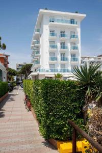 un grand bâtiment blanc avec un trottoir devant lui dans l'établissement Hotel Mirafiori, à Lido di Jesolo