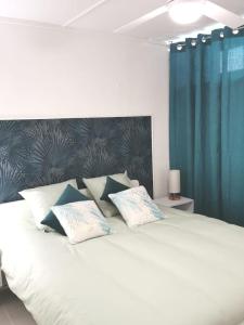 een slaapkamer met een wit bed en blauwe gordijnen bij Rez-de-jardin terrasse de 100m² in Le Grau-du-Roi