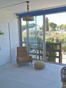a living room with a chair and a large window at Rez-de-jardin terrasse de 100m² in Le Grau-du-Roi