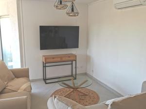 a living room with a tv and a table at Rez-de-jardin terrasse de 100m² in Le Grau-du-Roi