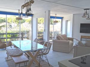 a living room with a glass table and chairs at Rez-de-jardin terrasse de 100m² in Le Grau-du-Roi
