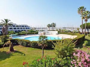 a swimming pool with palm trees and a resort at Rez-de-jardin terrasse de 100m² in Le Grau-du-Roi