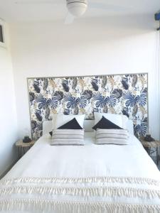 a bedroom with a white bed with a blue and white wallpaper at Rez-de-jardin terrasse de 100m² in Le Grau-du-Roi +16 photos