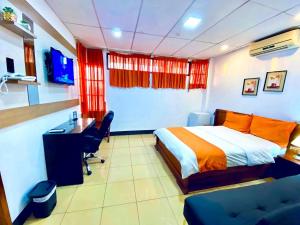 a bedroom with a bed and a desk and a computer at Hotel Madrigal in Portoviejo