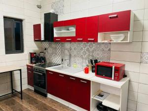 cocina con armarios rojos y microondas rojo en Appartement meublé T3 N 5 Résidence LES 11 PLURIELLES, 