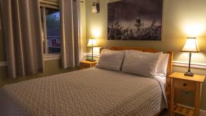 a bedroom with a bed with two lamps and a window at Wild Pacific Guest Suites in Ucluelet
