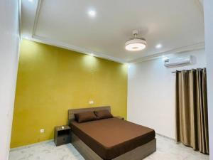1 dormitorio con cama y pared amarilla en Appartement meublé T3 N 5 Résidence LES 11 PLURIELLES, 