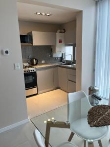 a kitchen with a glass table and a table and chairs at Departamento premium para 3 personas in Puerto Madryn