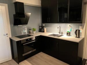 a kitchen with black cabinets and a sink at Ny Leilighet i Nevlunghavn in Larvik