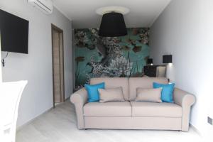 Incanto Luxury Rooms في لامبيدوسا: غرفة معيشة مع أريكة بيضاء مع وسائد زرقاء