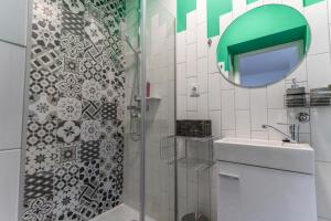 a bathroom with a shower with a sink and a mirror at Apartman Ana Osijek in Osijek