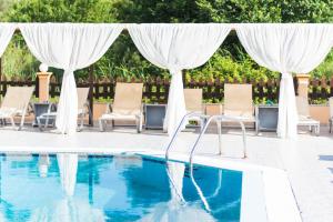 a swimming pool with chairs and a canopy and a swimming pool at Sandy Beach Complex - Annexe Building in Kavos +23 photos