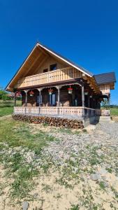 a large wooden building with a porch on a field at Casa bunicilor din Oncești in Onceşti