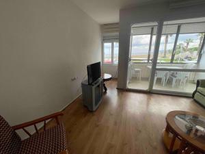 a living room with a tv and a table with chairs at Dikili Sahilde Denize Sıfır Daire in Dikili