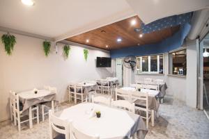 a dining room with white tables and chairs at Sandy Beach Annexe in Kavos
