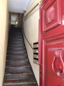 un escalier avec une porte rouge et un escalier. dans l'établissement Studio sur les toits du vieux Nîmes..., à Nîmes