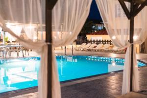 a pool with white curtains and chairs and a swimming pool at Sandy Beach Annexe in Kavos