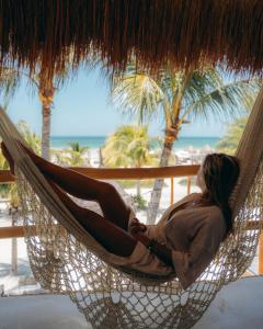 a woman laying in a hammock on a beach at Ser Casasandra Boutique Hotel in Holbox Island