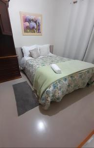a bedroom with a bed with a floral bedspread at Casa e Flat Conforto Gramado in Gramado