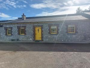 a stone house with a yellow door and windows at Castle Chalets in Cork