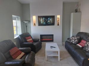 a living room with two leather couches and a fireplace at Castle Chalets in Cork