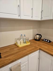 a kitchen counter with white cabinets and a tray with cups and bottles at Sweet Dream in Gdańsk