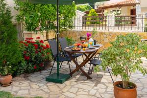 a table and chairs under an umbrella in a garden at Semeli House in Diakopto