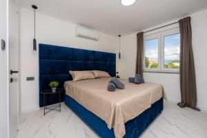 a bedroom with a large bed with a blue headboard at Vila Kety in Baška