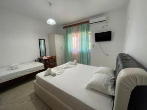 a hotel room with a bed and a television at Guesthouse Dollomaja Ksamil in Ksamil