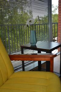 a table with a yellow chair and a vase on a balcony at Apartament Jaskółki w Pilicach in Jastrzębia Góra