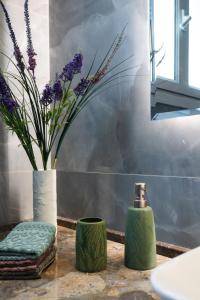 un baño con un jarrón con flores púrpuras en una encimera en Nina's Luxury Apartments, en Corfú