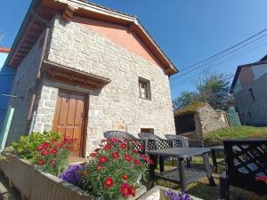 a small stone house with a table and flowers at Romántico acogedor apartamento en Llanes (Montaña) in Llanes