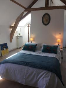 a bedroom with a large bed with a clock on the wall at 2 DESCARTES in La Flèche
